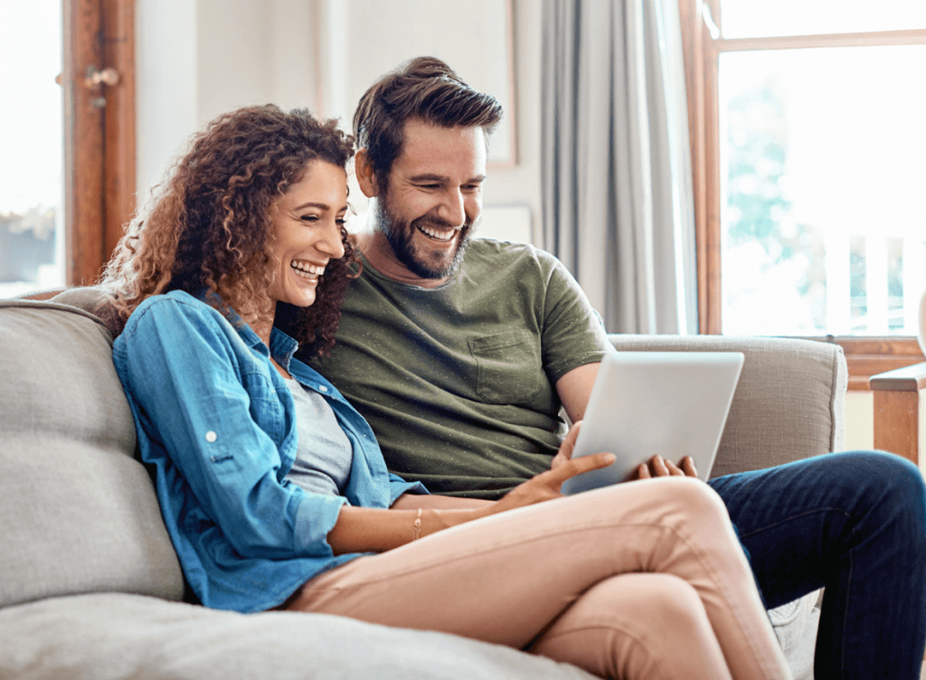 Couple on a sofa smiling looking at iPad Image